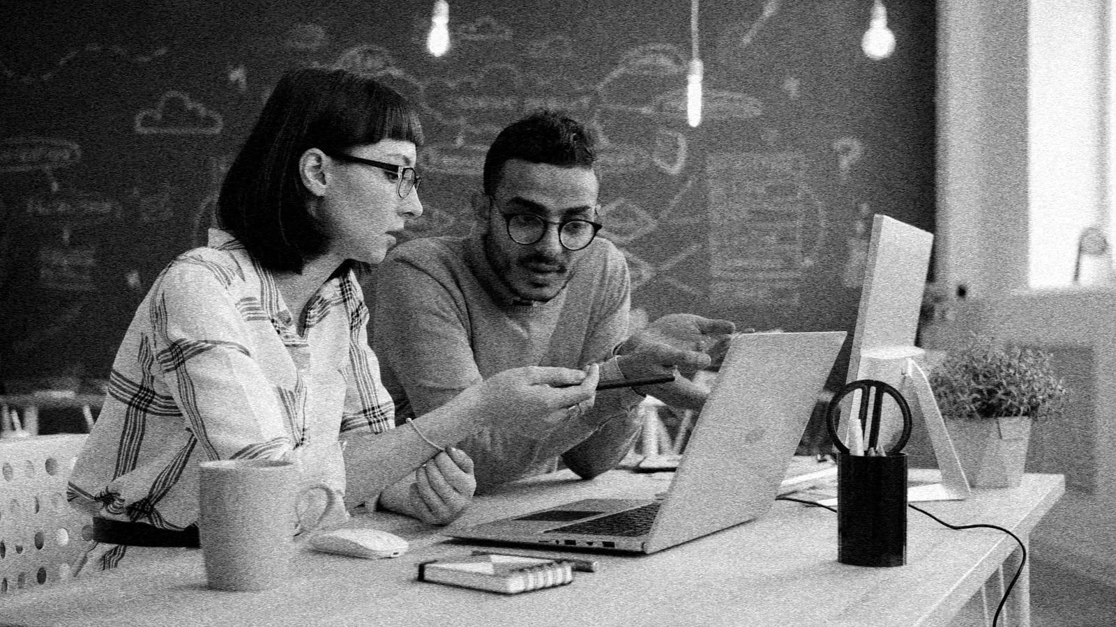 Eine Frau und ein Mann arbeiten gemeinsam an einem Laptop.
